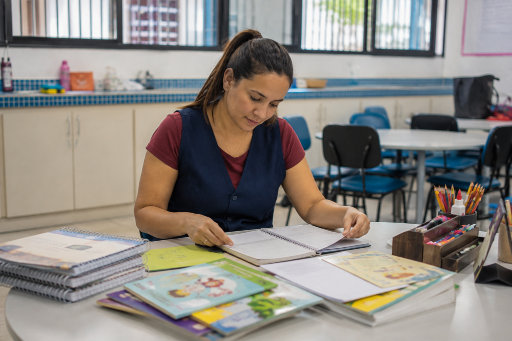 Professora da educação infantil preparando atividades pedagógicas em ambiente escolar.